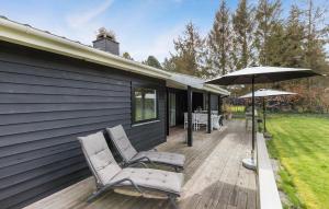 a deck with two chairs and an umbrella at Lovely Home In Dronningmlle With Kitchen in Dronningmølle