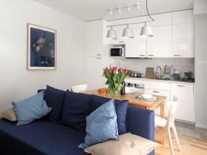 a living room with a blue couch and a kitchen at Metro Dzialdowska - Peace and comfort in Warsaw