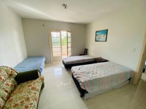um quarto com duas camas e um sofá e uma janela em Chácara com Piscina e Amplo Quintal em Embu