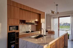 a kitchen with wooden cabinets and a sink at Om Cemagi Beach Villa Canggu in Canggu
