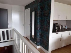 a kitchen with white cabinets and a staircase with a mirror at Wald Apartments im Predigtstuhl Resort in Sankt Englmar