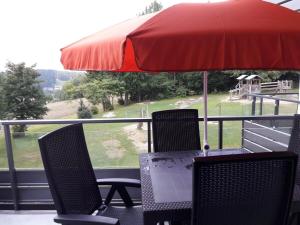 a table and chairs under an umbrella on a balcony at Wald Apartments im Predigtstuhl Resort in Sankt Englmar