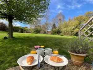 a table with two plates of croissants and orange juice at Cotswold Retreat - Private & Peaceful in Horley