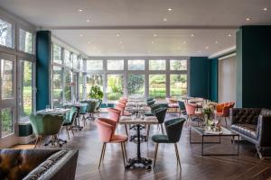 a restaurant with tables and chairs and windows at Whately Hall Hotel in Banbury