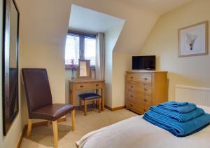 1 dormitorio con cama, silla y escritorio en Malthouse Lodge en Heacham