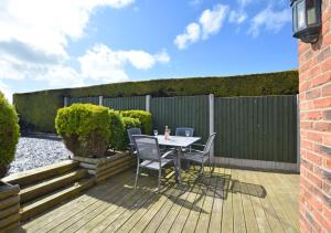 a patio with a table and chairs on a wooden deck at Malthouse Lodge in Heacham