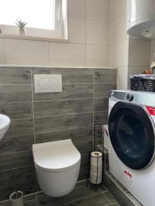 a bathroom with a toilet and a washing machine at Gabine - Self Check-in in Kaštela