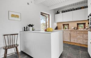 a kitchen with white cabinets and a counter with a chair at 1 Bedroom Pet Friendly Home In Egå in Egå