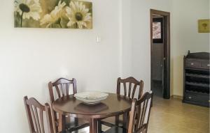 2 Bedroom Lovely Apartment In Villaviciosa في فيافيثيوسا: طاولة طعام مع كراسي و لوحة على الحائط
