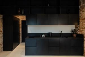 une cuisine avec des armoires noires et un mur en briques dans l'établissement Hortus Vilnius, à Vilnius 35 autres photos