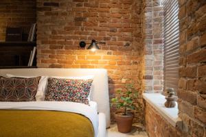 - une chambre aux murs de briques avec un lit et une plante dans l'établissement Hortus Vilnius, à Vilnius