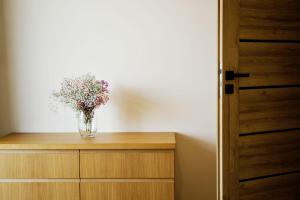 a vase of flowers sitting on top of a dresser at Apartament Thaddeus 48 z tarasem in Zator