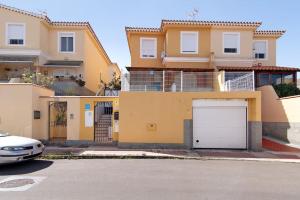una gran casa amarilla con garaje blanco en Casa Rural Los Vencejos, en Las Palmas de Gran Canaria