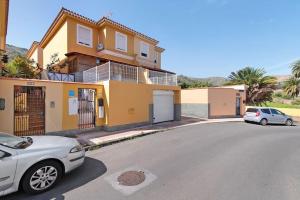 una casa amarilla con dos coches aparcados delante de ella en Casa Rural Los Vencejos, en Las Palmas de Gran Canaria