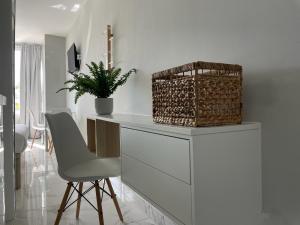 a white kitchen with a white counter and a chair at APTO Exelsior, Yumbo, Dunas y Playa in San Bartolomé de Tirajana