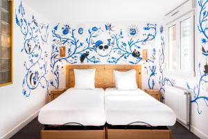 two beds in a room with blue and white wallpaper at Hôtel Graffalgar in Strasbourg