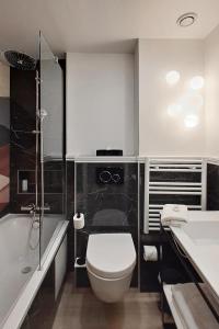 a bathroom with a toilet and a tub and a sink at Hotel Elysa-Luxembourg in Paris