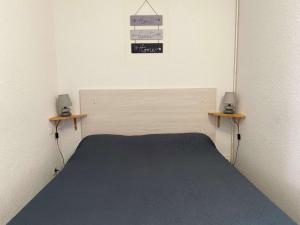 1 dormitorio con 1 cama y 2 mesas. en Appartement Balaruc-les-Bains, 1 pièce, 2 personnes - FR-1-553-35, en Balaruc-les-Bains
