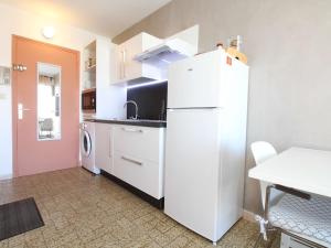 eine Küche mit einem weißen Kühlschrank und einem Tisch in der Unterkunft Studio Balaruc-les-Bains, 1 pièce, 2 personnes - FR-1-553-41 in Balaruc-les-Bains