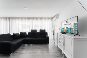 sala de estar con sofá negro y TV de pantalla plana en GuestReady - Amazing holiday home near the beach en Vila Nova de Gaia