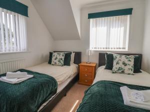 a bedroom with two beds and two windows at Wayside in Seaton