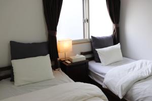 a bedroom with two beds and a lamp and a window at ホテル Shunju Kyotostation West 一日一組様限定 in Kyoto
