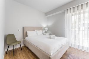 1 dormitorio blanco con 1 cama y 1 silla en GuestReady - Fantastic apt overlooking Douro river, en Oporto