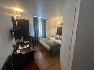 ein Hotelzimmer mit einem Bett und einem Schreibtisch mit einem Spiegel in der Unterkunft Logis Le Marronnier in Buffon