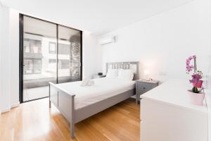 a white bedroom with a large bed and a window at GuestReady - Amazing Modern home near the beach in Vila Nova de Gaia