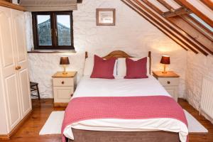 a bedroom with a large bed with red pillows at The Coach House in Bridgend