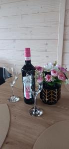 a bottle of wine and two glasses on a table with flowers at Domek Skitnica in Mirsk