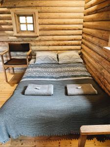 a bed in a log cabin with two towels on it at Araisi Windmill unique blend of history and nature in Cēsis