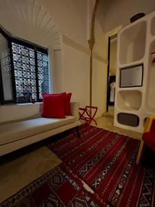 RiadLalZahra في الرباط: غرفة معيشة مع أريكة بيضاء ووسائد حمراء