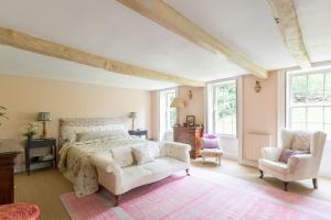 een slaapkamer met een groot bed en 2 stoelen bij Highgate House in Stroud