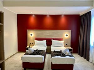 2 letti in una camera con parete rossa di Hotel Giacosa a Milano