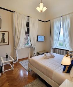 a bedroom with a bed with a lamp and two windows at Villa Nardi - Residenza D'Epoca in Florence