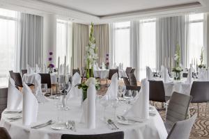 ein Esszimmer mit Tischen und Stühlen sowie weißen Tischdecken in der Unterkunft Steigenberger Hotel Bremen in Bremen