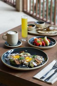 una mesa con platos de desayuno y un vaso de zumo de naranja en Boca de Agua Bacalar en Bacalar