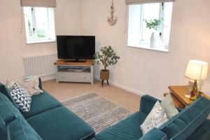 a living room with a blue couch and a tv at Seabreeze Cottage 2 bedroom - Sleeps 6 - Bron-Y-Wendon Holiday Park in Llanddulas