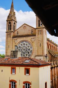 a church with a clock tower and a building at Le bijou des carmes - Haut de gamme climatisé in Toulouse
