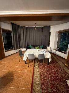 Хостел Aspan في ألماتي: غرفة معيشة مع طاولة وكراسي وأريكة