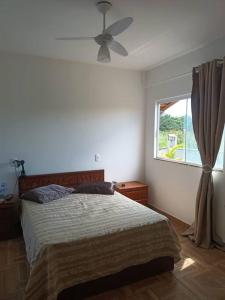 1 dormitorio con 1 cama con ventilador y ventana en Casa em São Francisco do Sul, Praia do Ervino, en São Francisco do Sul