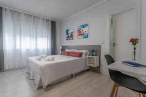 Un dormitorio con una cama con sábanas blancas y almohadas rojas. en Hotel Gabriel y Galán, en Salamanca