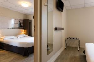 Cette chambre comprend un lit et une porte coulissante en verre. dans l'établissement The Originals City, Hôtel Clermont-Ferrand Sud Aubière, à Aubière