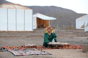 una mujer sentada en una manta con un plato de comida en la casa de othmane, en Marrakech