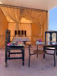 um quarto com duas cadeiras, uma mesa e uma cama em la casa de othmane em Marraquexe