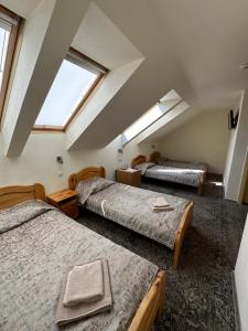 a attic room with three beds and two windows at Keta in Marijampolė