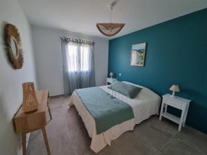 ein Schlafzimmer mit einem Bett und einer blauen Wand in der Unterkunft Le Mas des Cigales in Saumane-de-Vaucluse
