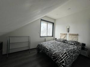 a bedroom with a bed with a black and white comforter at ARconciergerie Logement cosy centre-ville in Maisse