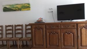 a tv sitting on top of a wooden cabinet with chairs at Gite de la margeride in Thoras